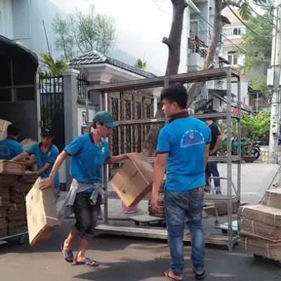 Nhân viên bốc xếp thùng hàng từ xe tải xuống xe đẩy trước nhà phố
