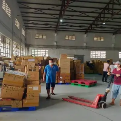 Nhân viên kiểm đếm thùng hàng bằng xe nâng tay trong kho